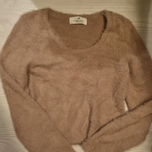 Beige fluffig stickad tröja H&M - Supermjuk och fluffig beige stickad tröja från H&M med rund halsringning och långa ärmar. Perfekt för dig som gillar mysiga och trendiga plagg med lite extra textur. Snygg att styla till både jeans och kjol.