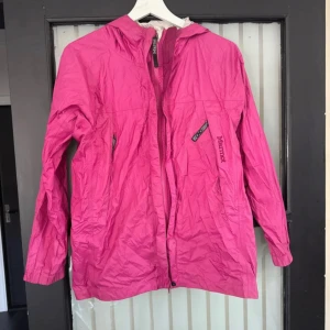 Rosa vindjacka från Marmot med huva - Snygg rosa vindjacka från Marmot med huva och dragkedja framtill, skrynklig på bild men i fint skick. Är storlek L men är väldigt liten så passar S-M.🌸