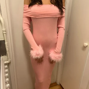 Rosa klänning off-shoulder med fluff  - Supersnygg & söt rosa ribbad midi/lång klänning med offshoulder och långa ärmar. Ärmsluten har fluffiga rosa fluff/fjädrar. Klänningen är figurnära och har en mjuk, stickad känsla som sitter perfekt! 💖💕⭐️💅🏼Använd 1 gång. Fraktar/möts upp i Solna! Kolla gärna mer plagg i min profil <3 Paketpris gäller! 
