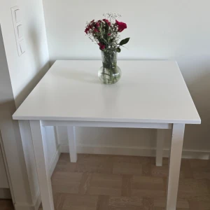 Bord - Ett vitt, enkelt träbord med ren design som fungerar utmärkt som matbord och passar lätt in i olika hem och inredningsstilar. Hämtas upp i Vasastan 