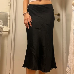 Svart Satinkjol  - Säljer en svart långkjol i satin med lätt utsvängd siluett. Passar till allt! Perfekt till hösten 💖 Fraktar/Möts upp i Solna. Kolla gärna min profil för mer kläder, paketpris gäller! <3
