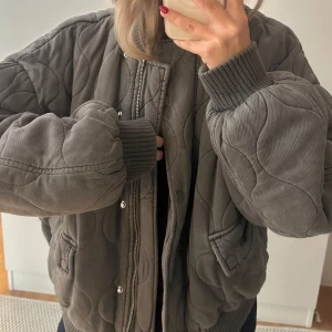 Grå quiltad bomberjacka från Zara - Quiltad och vadderad bomberjacka i grått från Zara, med oversized passform. Jackan har dragkedja och tryckknappar framtill samt två fickor. Väldigt varm/tjockt material! Jackan är endast använd 2-3 gånger. Säljer pga använder ej! Köpt för 899 kr. Säljer för 420 kr.