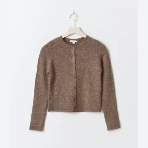 Ginatricot kofta beige - Mysig brun kofta i mjuk ull med rund halsringning och knäppning framtill. Klassisk modell med långa ärmar och enkel design som passar perfekt till lager-på-lager-stil. Perfekt för kyliga dagar.