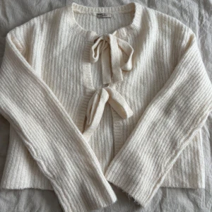 Kofta från Gina Tricot  - Superfin vit ribbstickad kofta från Gina tricot med två knytningar framtill. Storlek M. 