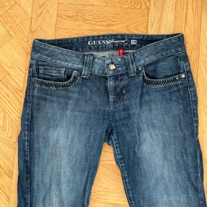 Blå jeans från Guess med nitar - Säljer min favvo jeans som är blåa flare jeans från Guess med coola nitar på! Innerbenslängd är 85cm och midjemåttet är 41❤️ Kom privat vid fler frågor!