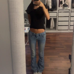 w23 True Religion ljusblå bootcut jeans - pris kan diskuteras. Säljer ett par ljusblå jeans från True Religion med bootcut passform och låg midja. Jeansen har klassiska fickor med lock och silverfärgade knappar bak, samt snygga sömdetaljer. Materialet är jeans och de har en cool, avslappnad vibe. w23 