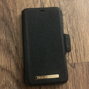 Magnetiskt skal iphone xr - Elegant svart plånboksfodral för iPhone XR från iDeal of Sweden. Fodralet har plats för kort och magnetisk stängning. Något slitage syns invändigt, men utsidan är i gott skick. Perfekt för dig som vill skydda din mobil med stil. Skickar endast via instabox