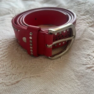 Rött vintage skärp - Snyggt rött bälte i skinn med silverfärgade nitar och coolt stansat stjärnmönster. Köpt i en vintage butik, fint skick 