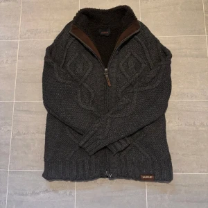 Kabelstickad-fodrad cardigan jacka - En riktigt snygg kabelstickad cardigan som är fodrad. Den är varm och tjock så passar som en jacka. Tyvärr för stor för mig. Priset kan diskuteras.