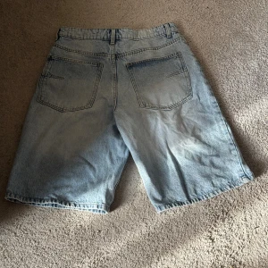 Ljusblå jeansshorts från Bershka - Säljer ett par ljusblå jeansshorts från Bershka med klassisk femficksdesign och normal passform. Shortsen har midwaist och är tillverkade i slitstarkt denim med snygg tvättad look. Perfekta för dig som gillar en chill och avslappnad streetwear stil.
