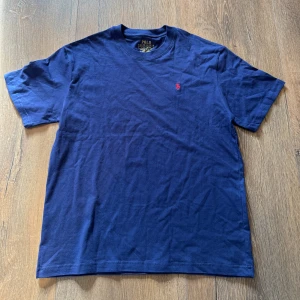 Marinblå t-shirt från Polo Ralph Lauren - Snygg marinblå t-shirt från Polo Ralph Lauren med klassisk röd broderad logga på bröstet. Står slimfit men passar regular fit/ vanlig L