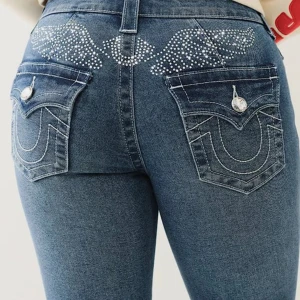 True Religion jeans  - Säljer nu dessa snygga blå jeans med vita kontrastsömmar, dekorativa bakfickor och strassdetaljer i form av vingar över bakdelen från True Religon. Jeansen har normal passform och är tillverkade i klassiskt jeanstyg. Aldrig använda stl 32-34 passar båda.😊