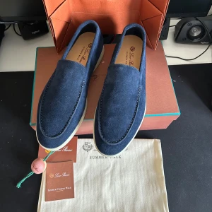 Loro Piana blå mockaloafers - Snygga loafers från Loro Piana i mörkblå mocka med vit sula. Modellen heter Summer Walk och har en klassisk, stilren design med rund tå och diskreta sömmar. Perfekta för dig som vill ha en clean och lyxig look.