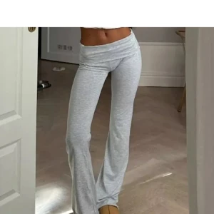 Grå mjukisbyxor från Nelly - Supermjuka och sköna ljusgrå mjukisbyxor från Nelly med låg midja och utsvängda ben. Perfekta för chill eller när du vill ha en avslappnad look. Byxorna är i bomullsmix och har en enkel, stilren design utan synliga detaljer.