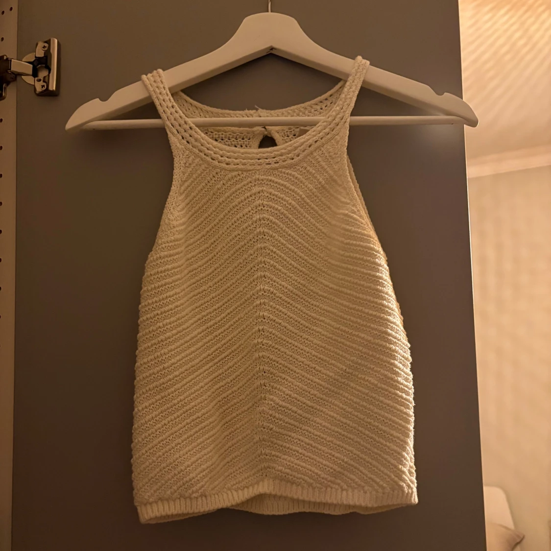 Vit stickad linnetopp med nyckelhålsdetalj