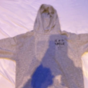 Grå hoodie med tryck från Gina Tricot - Säljer en grå hoodie från Gina Tricot med coolt svart tryck 'JE M'EN AMOUR' och en stjärna på framsidan. Tröjan har huva och långa ärmar, perfekt för chill dagar. Mjuk och skön bomullskänsla, passar dig som gillar enkel streetstil.