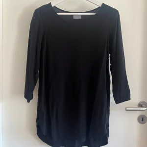 Svart långärmad topp från Vero Moda - Svart långärmad topp från Vero Moda i storlek L. Modellen har rund halsringning och trekvartsärm med knappdetalj. Toppens passform är normal och materialet känns mjukt och lätt. 