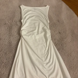 Vit ärmlös klänning från H&M Divided - Snygg vit ärmlös klänning från H&M Divided i storlek XXS. Klänningen har en enkel och stilren design med rund halsringning och lätt figurnära passform. Perfekt för dig som gillar minimalistisk stil och vill ha något bekvämt och fräscht.