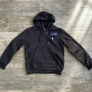 Svart Ralph Lauren zip hoodie - Säljer denna feta Ralph Lauren tröjan eftersom den inte passade mig när den köptes. Säljer den billigt för jag vill sälja den snabbt, och pris kan även diskuteras. Storlek XS och helt ny med lappen kvar. 😬🔥