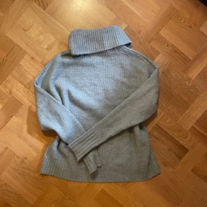 Ljus grön stickad polotröja - Mysig grå stickad polotröja med bred krage och långa ärmar. Tröjan har en relaxed fit och ribbade muddar vid ärmslut och nederkant. Perfekt för lager-på-lager och chill dagar.