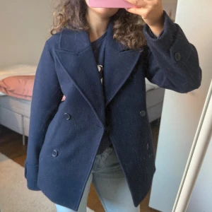 Mörkblå kort kappa med knappar - Säljer denna mörkblåa korta kappan, har använts några gånger men har inga defekter förutom att den är lite luddig💕