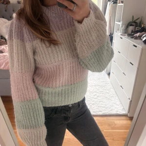 Pastellrandig stickad tröja - Supermysig stickad tröja med breda ränder i pastellfärger som lila, ljusrosa, mintgrön och offwhite. Tröjan har en ribbad rund hals och långa ärmar med relaxed fit. Från Vero Moda