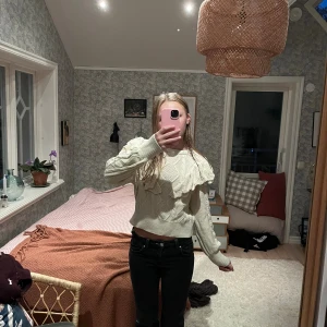 Beige stickad tröja med volang - Superfin beige stickad tröja från Only  med volangdetaljer över axlarna.Tröjan har rund halsringning, långa ärmar och ribbade muddar. Tröja är i storlek m och är aldrig använd.
