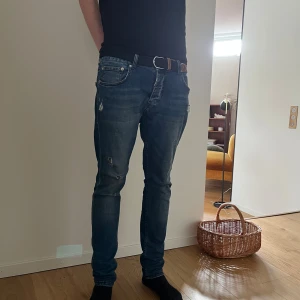 Dsquared2 jeans - Säljer ett par dsquared2 jeans i mörkblå tvätt med slitningar och slim/skinny passform. Klassisk femficksmodell med dragkedja och knapp. Jeansen har snygga detaljer och är tillverkade i stretchig bomullsmix för en bekväm känsla.