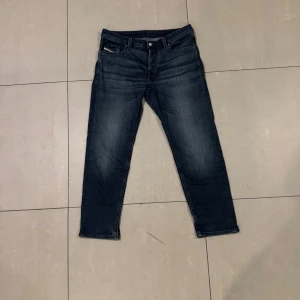 Mörkblå jeans från Diesel - Sköna mörkblå jeans från Diesel med klassisk femficksdesign och diskreta slitningar. Jeansen har raka ben och normal passform, perfekt för en avslappnad stil. Tillverkade i slitstarkt denimtyg. 32W30L