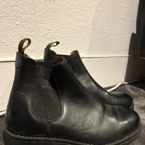 Svarta Chelsea boots från Gant, strl 42 - Snygga svarta Chelsea boots från Gant i skinn med klassisk rund tå och elastiska paneler på sidorna. Skorna har dragflikar med Gant-logga och en stilren, platt sula. Perfekta för dig som gillar tidlös och clean stil. Använda 1 gång 