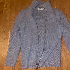 Ljusgrå ribbad kofta från Ljung - Säljer en ljusgrå ribbad kofta från Ljung by Marcus Larsson i storlek S. Koftan har dragkedja hela vägen, hög krage och är tillverkad i mjukt stickat material. Perfekt för lager-på-lager och chill vardagsstil.