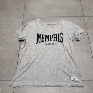 Grå t-shirt med Memphis-tryck - Grå T-shirt från Lager 157 med texten ”Memphis Tennessee” på. Storlek L. Mycket gott skick och knappt använd💕