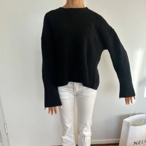 Svart stickad tröja från Other Stories - En svart stickad tröja från Other Stories med rund halsringning och breda ribbade muddar vid ärmslut och nederkant. Tröjan har en loose passform och är långärmad, perfekt för lager-på-lager under kyliga dagar.