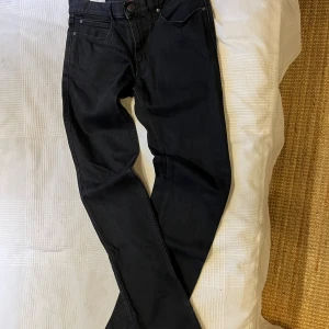 Svarta jeans från Hugo Boss - Svarta jeans från Hugo Boss med klassisk femficksdesign och snygga detaljer som röd insida och logotyp. Jeansen har raka ben och normal passform, tillverkade i bomull med en hint av stretch för extra komfort.