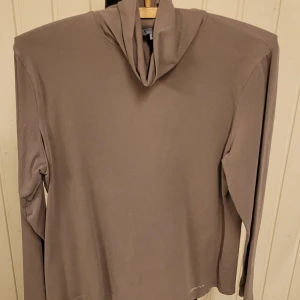 Beige polotröja från CPM Edition - Snygg beige polotröja från CPM Edition i storlek 46. Tröjan har lång ärm och en hög, mjuk polokrage som ger en chill vibe. Tillverkad i skönt bomullsmaterial, perfekt för dig som gillar enkel och stilren look.