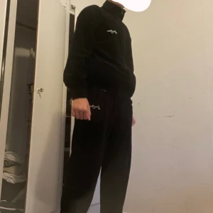 Svart zip hoodie från Sohn John - Svart hoodie från Sohn John i mjuk sammet med dragkedja framtill och hög krage. Långärmad modell med broderad logga på bröstet. Passar dig som gillar chill och stilren look. Perfekt till höst och vinter när du vill vara både bekväm och snygg. Priset kan diskuteras 450kr vid Snabbaffär