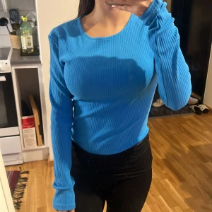 Blå ribbad topp med öppen rygg Gina Tricot - Säljer en blå långärmad ribbad body från Gina Tricot i storlek S. Toppen har en snygg öppen rygg med och är tillverkad i stretchigt material. Perfekt för dig som vill ha något unikt och trendigt i garderoben!