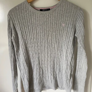 Grå kabelstickad tröja Gina Tricot - Grå tröja. En fläck på baksidan av tröjan. Har inte lagt jättestor tid på att få bort den