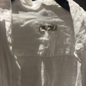 Vit linneskjorta från Puro Lino - Säljer en vit skjorta från Puro Lino i 100% linne. Skjortan har klassisk krage, knäppning framtill och långa ärmar. Perfekt för en chill och stilren look under varmare dagar. Tillverkad i Italien och har en luftig känsla.