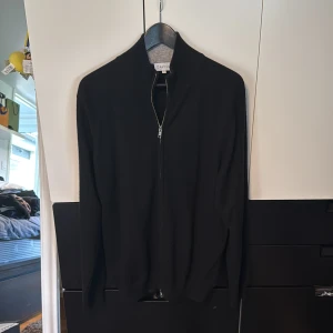 Davida kashmir tröja - Svart kofta från Davida i 100% kashmir med dragkedja framtill och hög krage. Stilren och mjuk design med långärmade ärmar och ribbad insida på kragen. Perfekt för dig som gillar klassiska och bekväma plagg med lite lyxig känsla. Använd väldigt fåtal gånger är som ny, nypris 2899kr