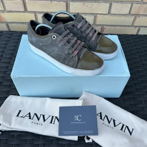 Lanvin - Snygga sneakers från Lanvin i grå mocka och lackad tå, skicket är använt men de är redo att användas igen, lite repig toebox och snörena är lite missfärgade går att köpa nya för billigt, hälen är tejpad men märks inte av, uk 5 som är ungefär 40-41, pris går att diskutera, obs sulkräm har använts. Boxen och skorna ingår bara! dustbag och kort ingår inte 