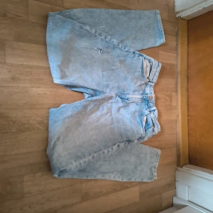 Ljusa relaxed jeans HM - Säljer ett par ljusblå relaxed fit jeans från &Denim med hög midja. Modellen har raka ben, klassiska fem fickor och justerbar midja med knappresår. Perfekt för dig som gillar en loose och chill stil.