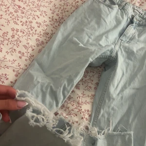 Ljusblå jeans från Zara med fransig kant - Säljer ett par ljusblå jeans från Zara med raka ben och snyggt fransiga benslut. Klassisk femficksmodell med dragkedja och knapp. Perfekta för en avslappnad och trendig look.