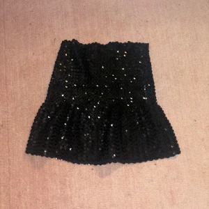 Svart paljettkjol med volang - Glittrig minikjol köpt vintage i London i färg svart står ingen storlek men skulle säga att det är en S/M. Super fin och går att matcha till allt. Kjolen är i topp skick