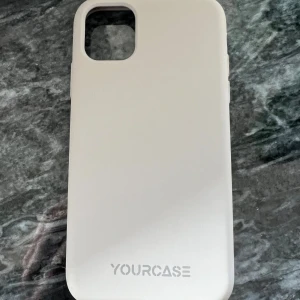 YOURCASE iPhone Skal - Stilrent vitt skal från YOURCASE, designat för iPhone med fyrkantigt kamerauttag. Skalet är i gott skick med mindre tecken på användning invändigt. Ger bra skydd mot repor och stötar, perfekt för dig som vill hålla din iPhone fräsch och snygg.