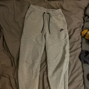 Grå mjukisbyxor nike tech. - Snygga grå mjukisbyxor från Nike i storlek XS. Byxorna har svart snörning i midjan, två sidofickor och klassisk Nike-logga på vänster ben. 