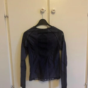 Mörkblå långärmad träningströja ICANIWILL - Säljer en mörkblå långärmad träningströja från ICANIWILL. Tröjan har ventilerande meshdetaljer på axlarna och är tillverkad i ett stretchigt syntetmaterial som passar perfekt för gym eller löpning.