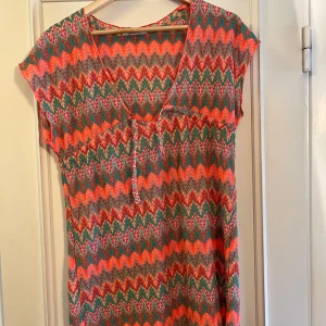 Färgglad strand klänning Primark - Superfin strand klänning från Primark med färgstarkt mönster i orange, grönt och rosa. Klänningen har v-ringning, korta ärmar och ett stickat, nästan virkat material. Perfekt för dig som gillar att sticka ut med färg och mönster! Skickar fler bilder vid intresse💞