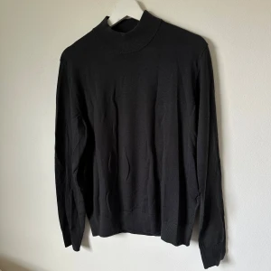 Mörkgrå polotröja från Uniqlo i ull - Mörkgrå polotröja från Uniqlo i storlek S, tillverkad i 100% ull. Tröjan har en hög krage och långa ärmar med ribbade muddar vid hals, ärmslut och nederkant. Enkel och stilren design som funkar till många olika looks. 2I1