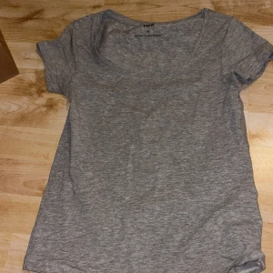 Grå basic t-shirt från 157, XS - Enkel grå t-shirt från 157 i storlek XS. T-shirten har rund halsringning och korta ärmar. Tillverkad i mjuk bomullsblandning med lite stretch för extra komfort. Perfekt till jeans eller shorts.